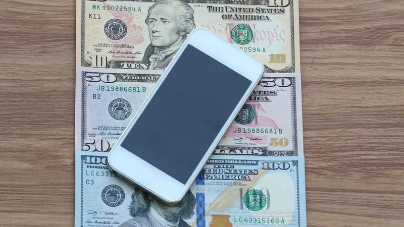 Mobile phone on dollar cash banknote, digital money and finance technology concept