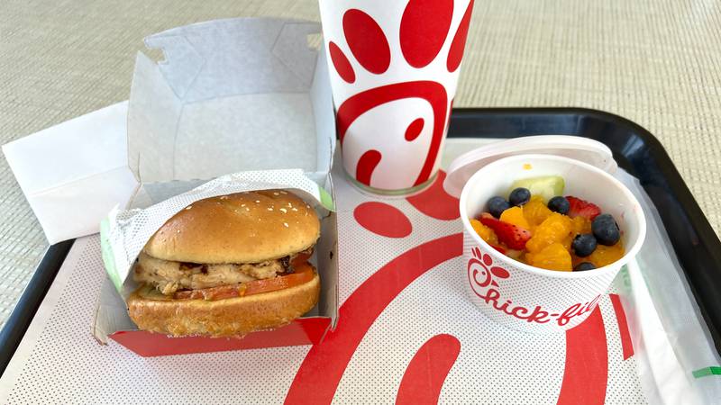 Close up on Grilled Chicken Sandwich and fruit cup with soda cup in background on a serving tray at Chick-fil-a fast food restaurant.