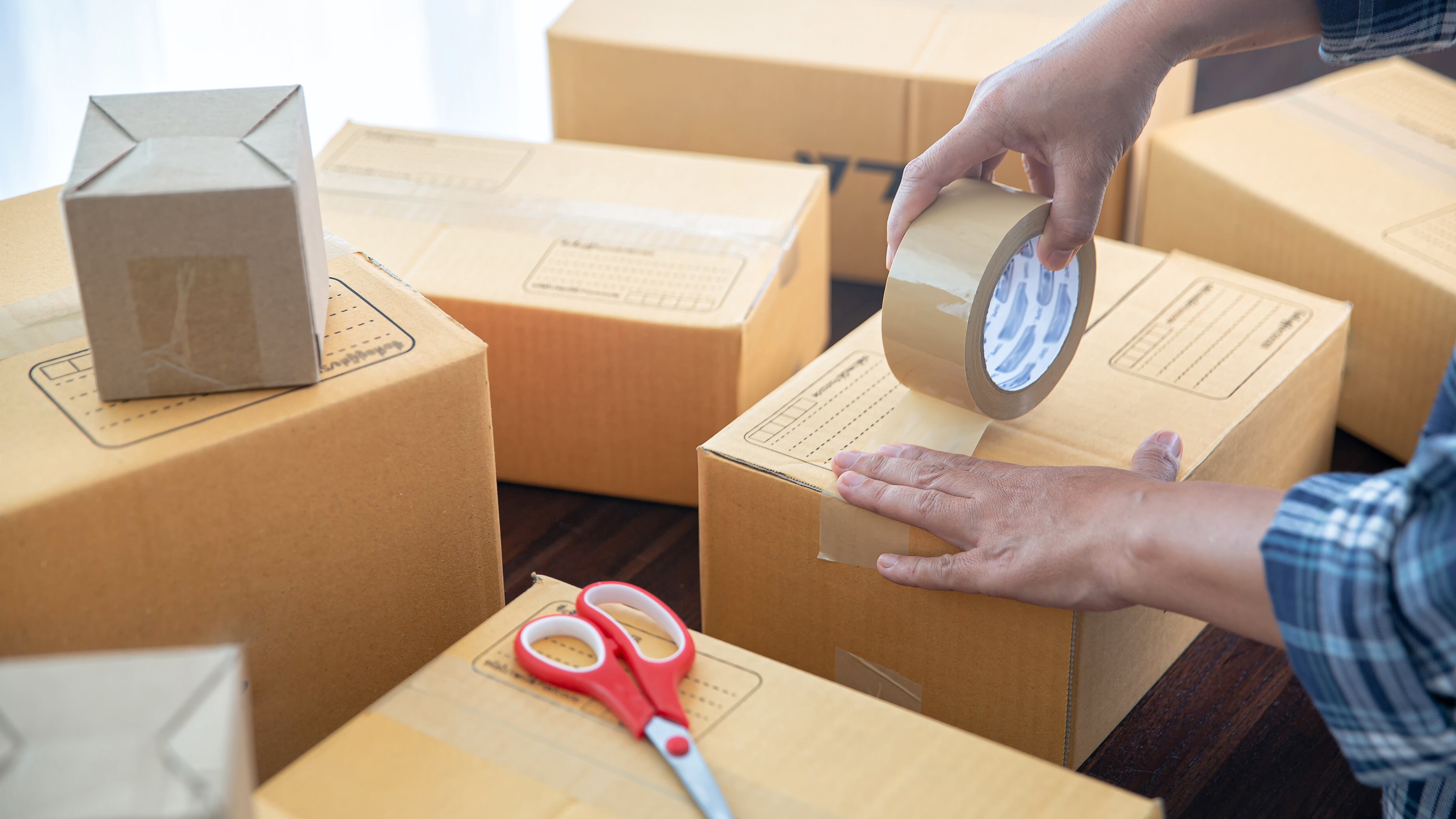 Closeup view of a person packing shipping box, preparing to send